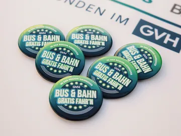 Buttons mit der Aufschrift Bus und Bahn Gratis Fahr'n liegen auf einem Tisch
