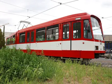 TW 601 auf einem Betriebshof. Die Bahn ist rot und hat einen breiten weißen Streifen unterhalb der Fenster, die über die gesamte Fahrzeuglänge geht.