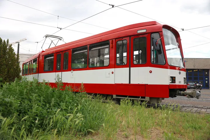 TW 601 auf einem Betriebshof. Die Bahn ist rot und hat einen breiten weißen Streifen unterhalb der Fenster, die über die gesamte Fahrzeuglänge geht.