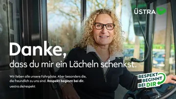 Eine Fahrerin sitzt am Bus-Lenkrad und lächelt freundlich in die Kamera.