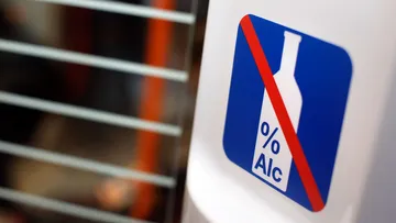 Aufkleber in einer Stadtbahn, der eine durchgestrichene Alkoholfalsche auf blauem Hintergrund zeigt. 