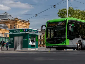 Ein ÜSTRA Bus steht auf der Straße vorm Hauptbahnhof, links daneben ist der ÜSTRA Servicepoint zu sehen, im Hintergrund der Hauptbahnhof. 