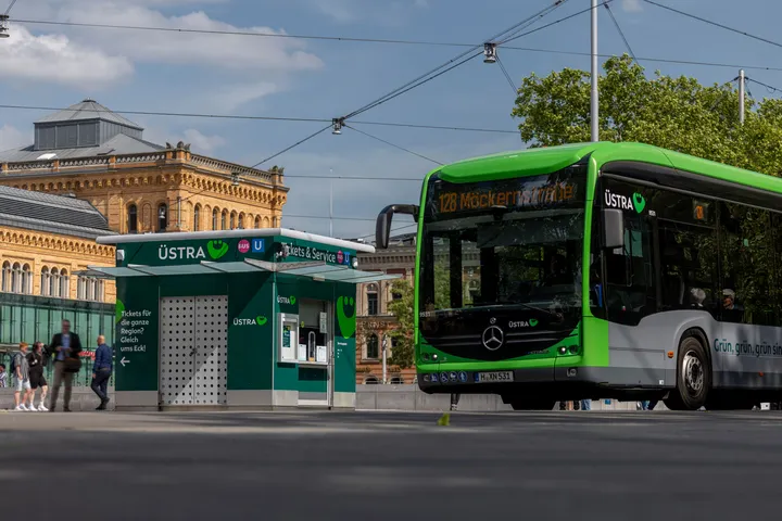 Ein ÜSTRA Bus steht auf der Straße vorm Hauptbahnhof, links daneben ist der ÜSTRA Servicepoint zu sehen, im Hintergrund der Hauptbahnhof. 