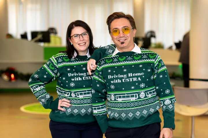 Eine Frau und ein Mann tragen denn "ugly christmas sweater" der ÜSTRA aus dem Jahr 2025.