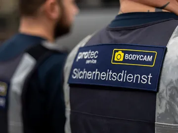 Der Rücken zweier protec-Mitarbeiter, die mit einem Aufnäher mit der Aufschrift Aicherheitsdienst und Bodycam versehen sind.
