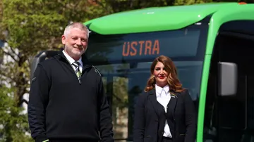 Fünf ÜSTRA Mitarbeitende in Dienstkleidung stehen vor einem Stadtbus