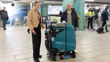 ÜSTRA Vorständin Elke van Zadel und protec Geschäftsführer Mathias Lindscheid präsentieren in der Station Kröpcke den neuen Wischroboter. Um sie herum stehen Menschen.