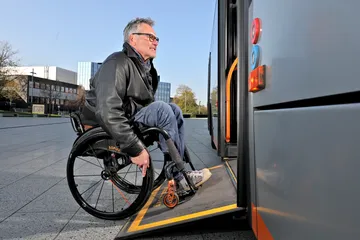 Ein Rollstuhlfahrer fährt über die Rampe in einen Bus ein.