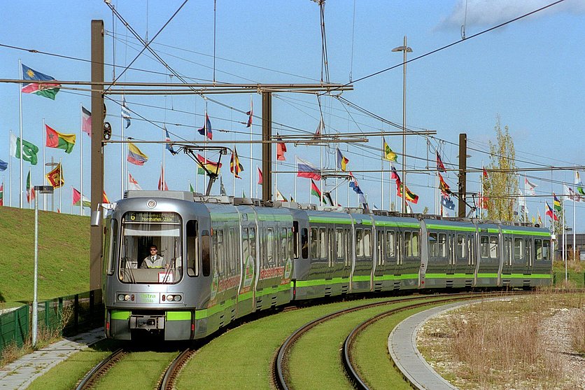 Bild von einem TW 2000 bei der Fahrt. Im Hintergrund und an der Seite befinden sich Fahnen der Expo.