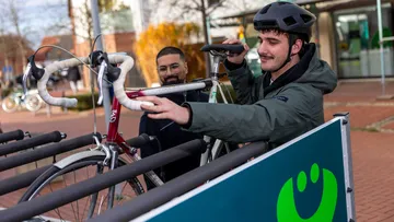 Ein Mann mit Fahrradhelm lädt ein Rennrad auf den Anhänger des Fahrradbusses auf.