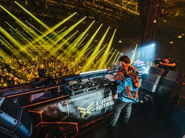 DJ steht in Messehalle bei einem großen Festival mit vielen Besuchern 