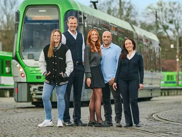 Mehrere Mitarbeitende der ÜSTRA stehen vor einer Stadtbahn.