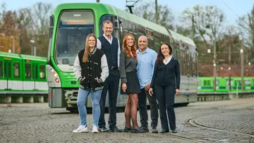 Mehrere Mitarbeitende der ÜSTRA stehen vor einer Stadtbahn.