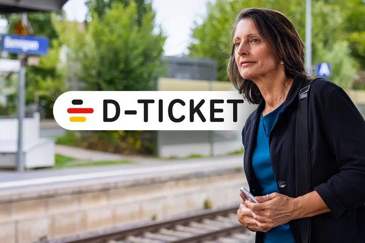 Berufstätige Frau mit Deutschland Jobticket steht am Gleis und wartet auf ihre Bahn