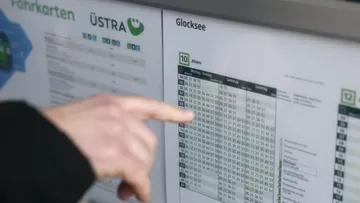 Eine Hand folgt mit ausgestrecktem Zeigefinger den Zeilen einer Fahrplantabelle