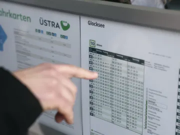 Eine Hand folgt mit ausgestrecktem Zeigefinger den Zeilen einer Fahrplantabelle