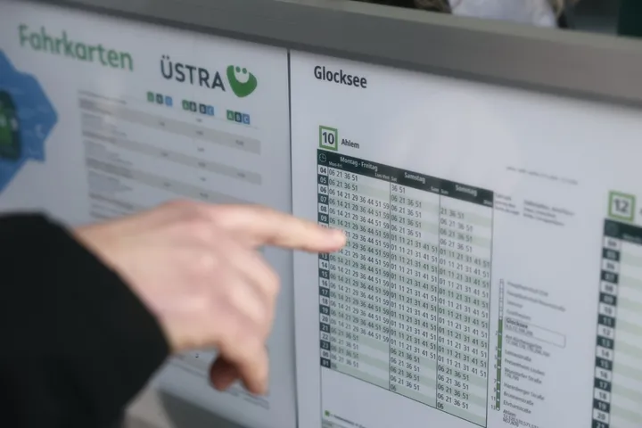 Eine Hand folgt mit ausgestrecktem Zeigefinger den Zeilen einer Fahrplantabelle