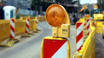 Baustellenschilder und Absperrzäune an einer Straße.