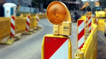 Baustellenschilder und Absperrzäune an einer Straße.