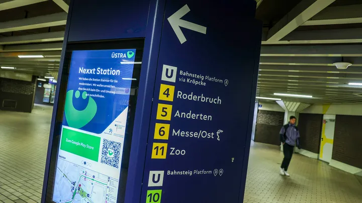 Eine Säule in der Station Steintor mit zwei Seiten. Auf der linken Seite ist ein Monitor im Hochkant-Format. Auf dem Monitor ist ÜMO zu sehen und ein Umfeldkarte vom Steintor. Auf der rechten Seite der Säule zeigt ein Pfeil nach links. Darunter stehen das U-Symbol mit dem Text "Bahnsteig Platform 2 via Kröocke" und die Linien 4, 5, 6 und 11 mit den jeweiligen Endpunkten Roderbruch, Anderten, Messe/Ost und Zoo. Darunter ist noch ein U-Symbol mit dem Text "Bahnsteig Platform 3 und 4" und die Linien 10 und 17.