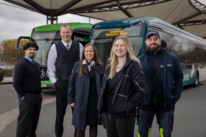 Fünf Mitarbeiter*innen von regiobus und ÜSTRA stehen vor einem regiobus und einem ÜSTRA Linienbus.