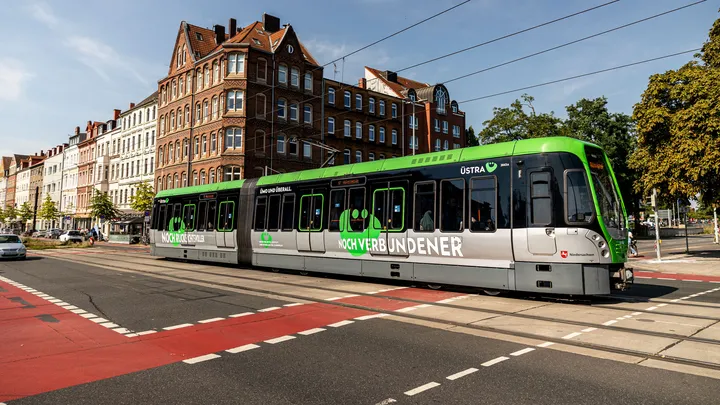 Ein fahrender T W 3000 mit einer großen Beklebung an der Seite. Auf der Beklebung steht "noch verbundener" und das ÜMO.