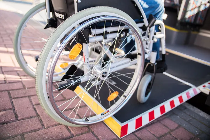 Nahaufnahme der Räder eines Rollstuhls, der über eine Rampe in einen Bus fährt