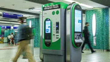 ÜSTRA Fahrkartenautomat an der Station Kröpcke, es laufen unscharf Passanten davor entlang