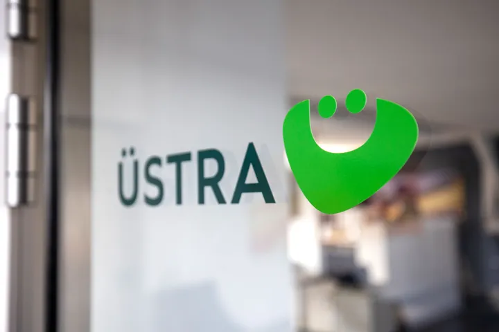 Das Logo der ÜSTRA auf einer Glastür. Im Hintergrund sieht man verschwommen ein Büro.