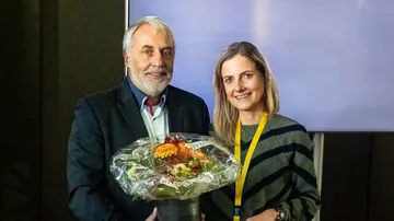 Michael Neugebauer (Göttinger Verkehrsbetriebe) übergibt den VDV Landesgruppenvorsitz an die Vorstandsvorsitzende der ÜSTRA, Elke Maria van Zadel und gratuliert mit einem Blumenstrauß.