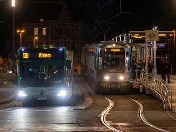 Zu sehen sind ein Bus und eine Stadtbahn an einer Haltestelle. Es ist Nacht. 