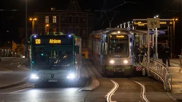 Zu sehen sind ein Bus und eine Stadtbahn an einer Haltestelle. Es ist Nacht. 
