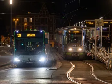 Zu sehen sind ein Bus und eine Stadtbahn an einer Haltestelle. Es ist Nacht. 