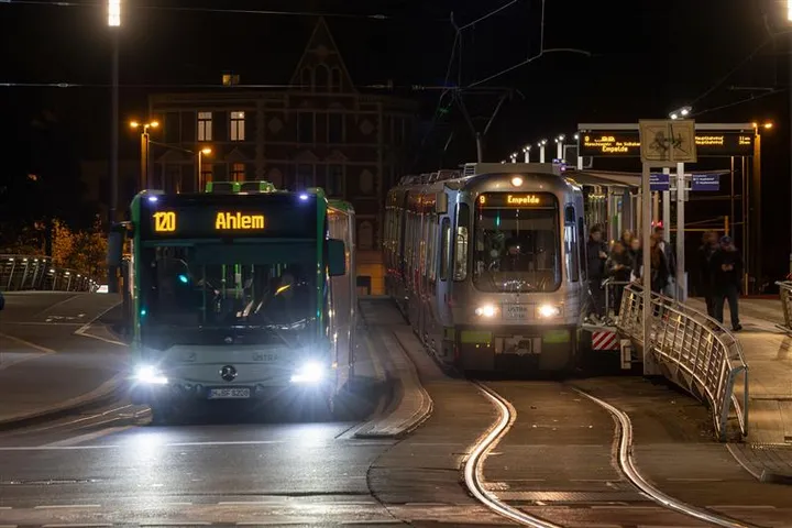 Zu sehen sind ein Bus und eine Stadtbahn an einer Haltestelle. Es ist Nacht.