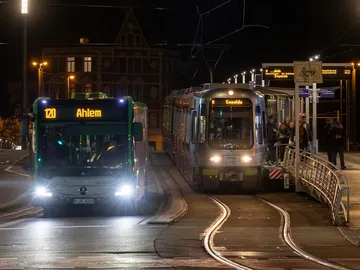 Zu sehen sind ein Bus und eine Stadtbahn an einer Haltestelle. Es ist Nacht. 