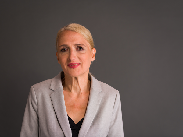 Portraitaufnahme von Regina Oelfke vor einer grauen Wand 