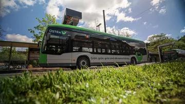 Ein Elektrobus der Marke Mercedes steht am August-Holweg-Platz in Hannover. Der Bus lädt gerade die Batterien über die Ladesäule auf. Auf dem Bus ist eine Werbung mit dem  Slogan "Grün, grün, grün, sind alle meine Fahrten!" angebracht.