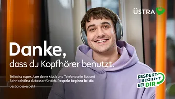 Ein junger Mann trägt Kopfhörer und lächelt freundlich in die Kamera. 