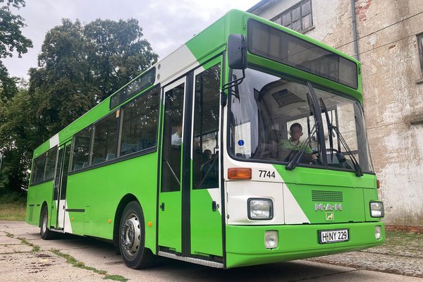 Ein ÜSTRA Oldtimer mit der Wagennummer 7744 von MAN steht vor einem Gebäude.