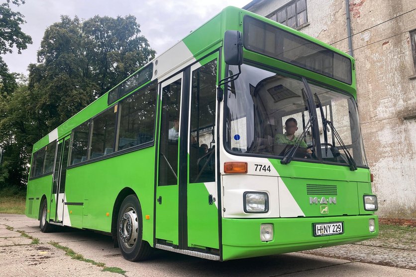 Ein ÜSTRA Oldtimer mit der Wagennummer 7744 von MAN steht vor einem Gebäude.