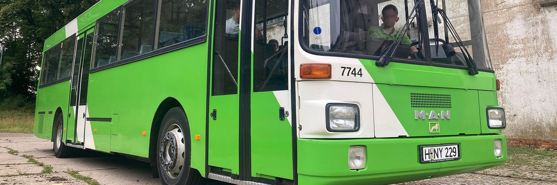 Ein ÜSTRA Oldtimer mit der Wagennummer 7744 von MAN steht vor einem Gebäude.