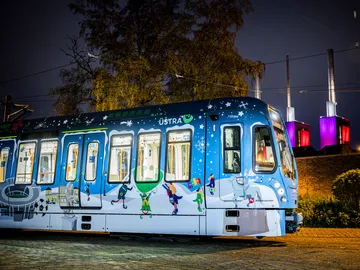 Winterbahn 2024 steht beleuchtet vor den ebenfalls bunt beleuchteten drei warmen Brüdern in Hannover