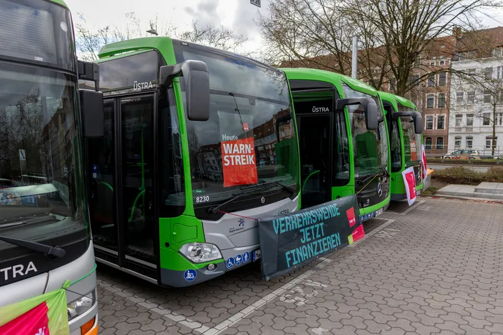 Vier Busse stehen nebeneinander auf dem Betriebshog und sind mit ver.di Streikpostern und Bannern "geschmückt".