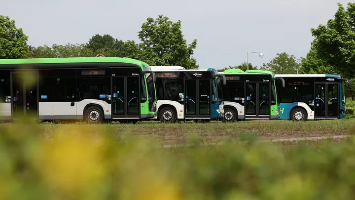 Vier Busse stehen hintereinander versetzt auf einem Betriebshof.