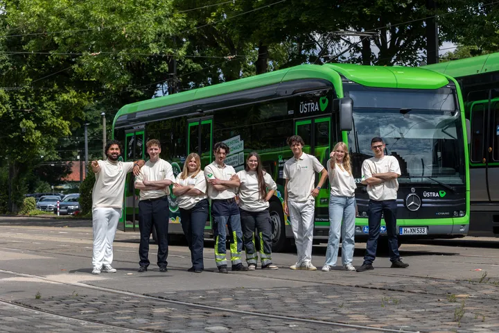 Azubis der ÜSTRA stehen als Gruppe vor einem Bus. 