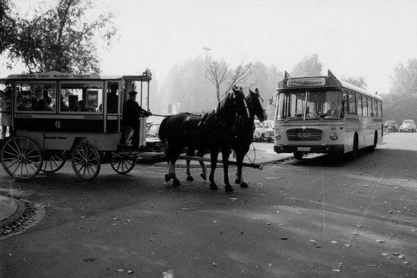 Ein Pferdebus mit Linie 9 trifft an einer Kreuzung einen Kraftomnibus von MAN.
