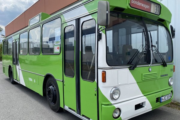Ein ÜSTRA Oldtimer mit der Wagennummer 7000. steht vor einem Gebäude.