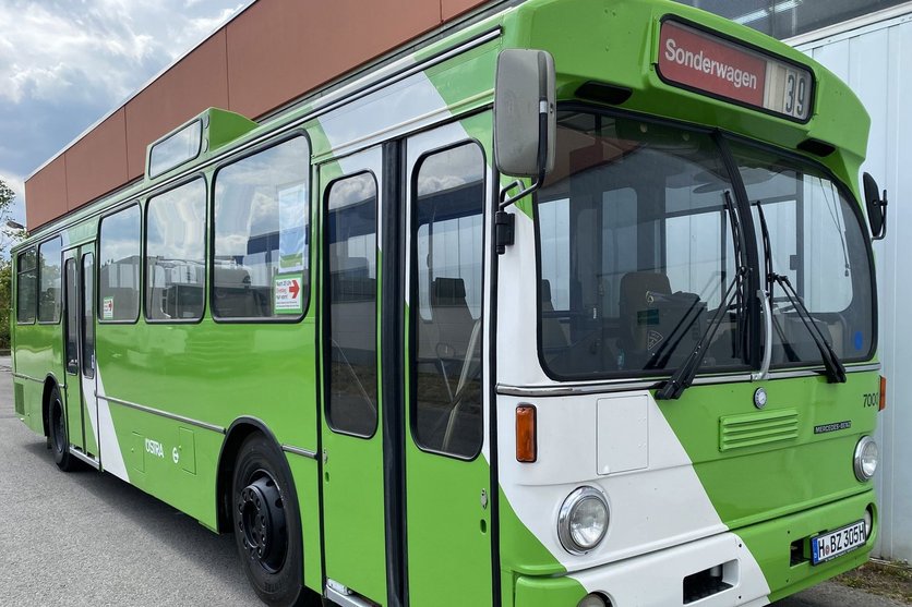 Ein ÜSTRA Oldtimer mit der Wagennummer 7000. steht vor einem Gebäude.
