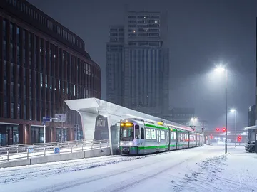 Ein TW 2000 steht am Hochbahnsteig Raschplatz/ZOB. Es ist Nacht, auf der Straße liegt Schnee, der von Straßenlaternen erleuchtet wird.