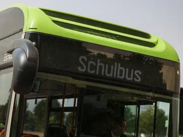 Zu sehen ist die digitale vordere Anzeige eines schwarzgrünen Busses. In der Anzeige steht "Schulbus".